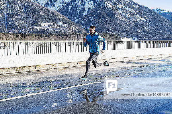 Deutschland  Bayern  sportlicher Mann läuft im Winter auf einer Straße