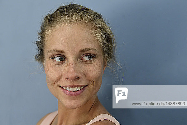 Porträt einer lächelnden jungen blonden Frau  die zur Seite schaut