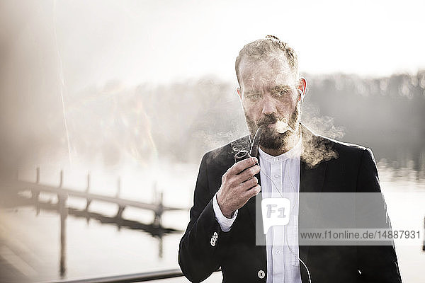 Geschäftsmann auf einer Hauspfeife stehend  Pfeife rauchend