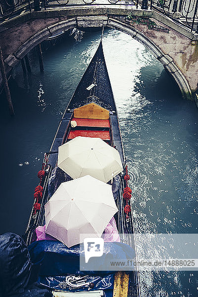 Italien  Venedig  Touristen in einer Gondel  die wegen heftigen Regens unter Regenschirmen geschützt sind