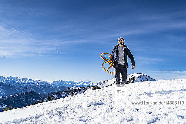 Deutschland  Bayern  Brauneck  Mann mit Schlitten im Winter in den Bergen