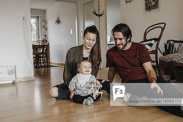 Glückliche Familie mit einem kleinen Mädchen  das zu Hause auf dem Boden sitzt