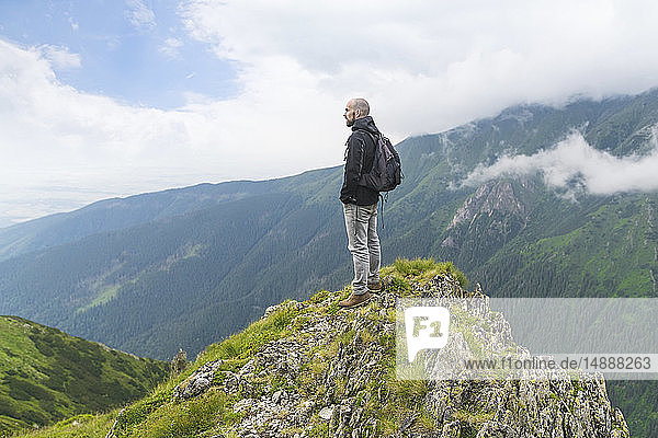Mann  der auf einem Hügel steht und auf die Landschaft in den Karpaten schaut  Rumänien