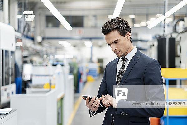 Businessman using cell phone in a factory