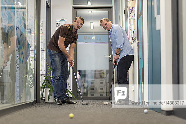 Zwei Geschäftsleute spielen Golf im Amt