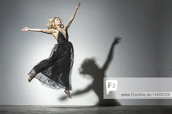 Blonde Frau tanzt in schwarzem Kleid