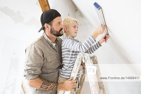Vater und Sohn arbeiten am Dachbodenausbau unter Verwendung des Wasserstandes