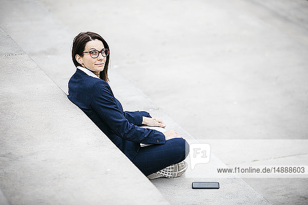 Porträt einer Geschäftsfrau  die mit Laptop im Freien auf einer Treppe sitzt