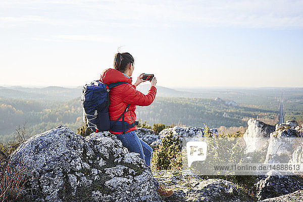 Frau auf einer Wanderung in den Bergen beim Fotografieren mit dem Smartphone