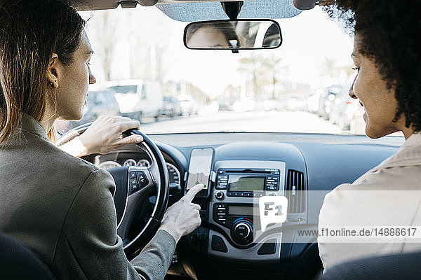 Zwei Frauen fahren in einem Auto durch die Stadt und nutzen eine telefonische Navigationsanwendung