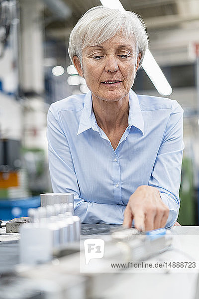 Porträt einer leitenden Geschäftsfrau in einer Fabrik  die ein Werkstück betrachtet