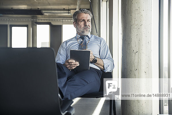 Mature businessman sitting on chair using tablet