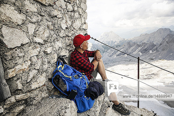 Österreich  Tirol  Mann auf Wanderung  der sich auf einer Berghütte ausruht und die Aussicht betrachtet