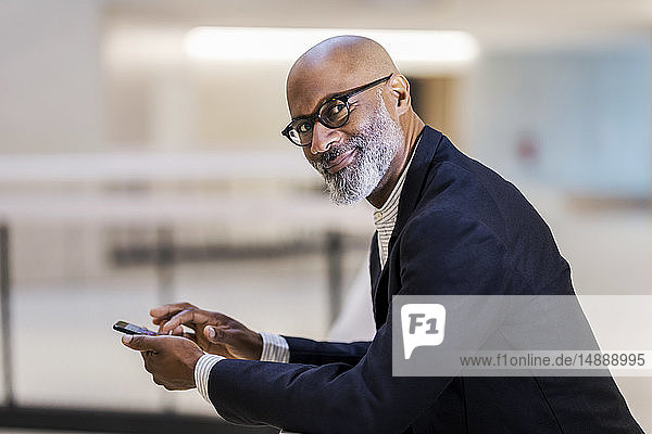 Porträt eines lächelnden reifen Geschäftsmannes mit Handy
