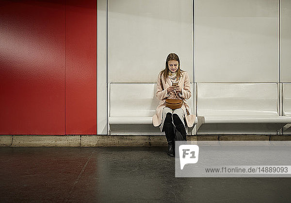 Österreich  Wien  junge Frau wartet in U-Bahn-Station mit Smartphone