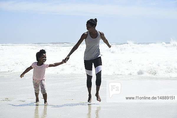 Happy mother and daughter having fun on the beach