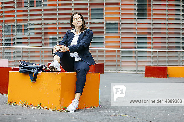 Geschäftsfrau  die vor einem Bürogebäude in der Stadt sitzt