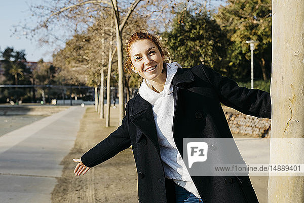 Porträt einer glücklichen rothaarigen jungen Frau in einem Stadtpark