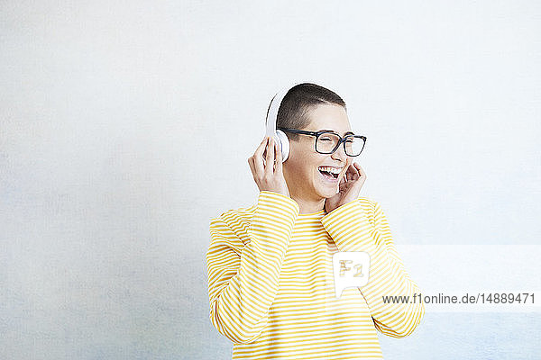 Glückliche junge Frau  die mit Kopfhörern Musik hört