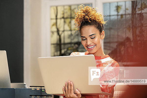 Junge Frau arbeitet in einem Modegeschäft und benutzt einen Laptop