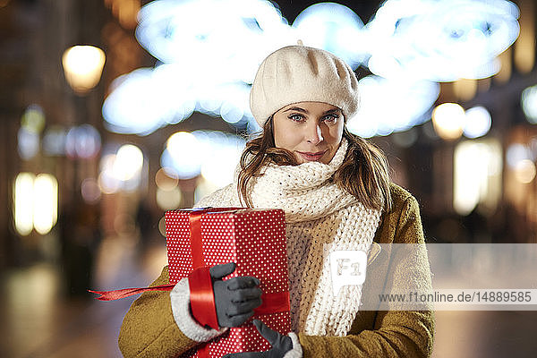 Portrait of smiling woman with Christmas present in the evening
