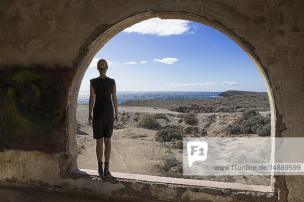 Spanien, Teneriffa, Abades, Sanatorio de Abona, Frau am Bogenfenster im Geisterstadtgebäude stehend