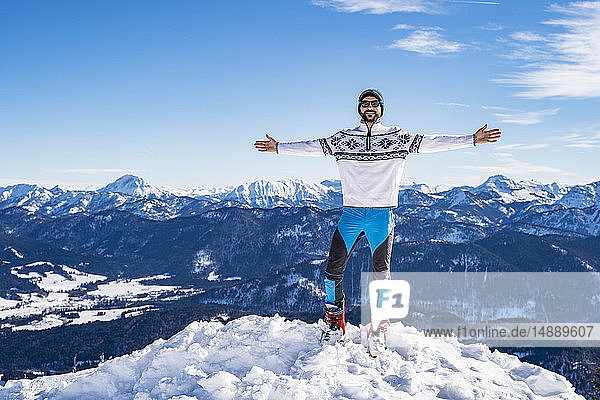 Deutschland  Bayern  Brauneck  glücklicher Mann im Winter auf dem Berggipfel stehend