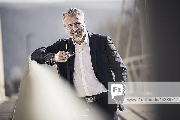 Porträt eines lächelnden  selbstbewussten  reifen Geschäftsmannes auf einer Brücke