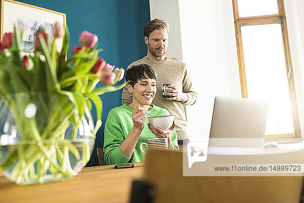 Glückliches Paar schaut sich Laptop im Heimbüro an