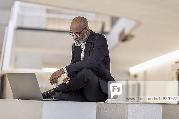 Bald mature businessman looking at laptop thinking
