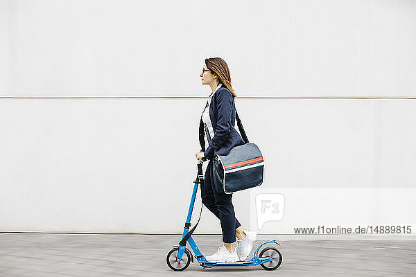 Active businesswoman riding scooter in the city