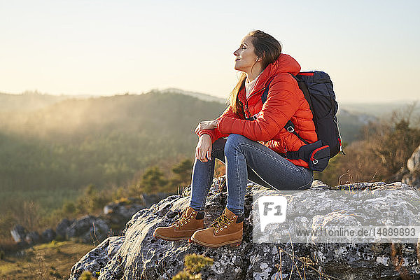 Frau auf einer Wanderung in den Bergen  die sich auf einem Felsen ausruht