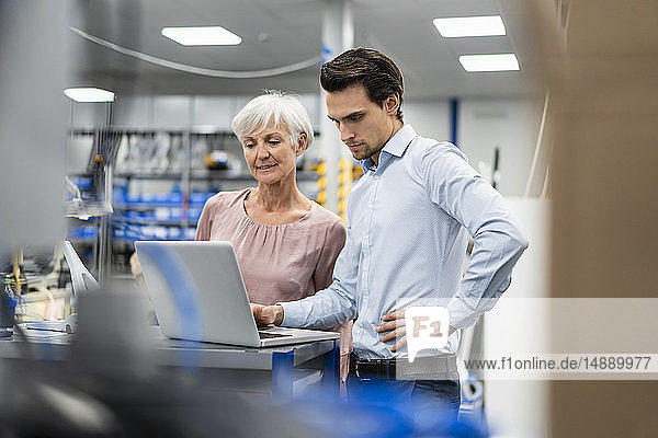Geschäftsmann und leitende Geschäftsfrau  die in einer Fabrik am Laptop arbeiten