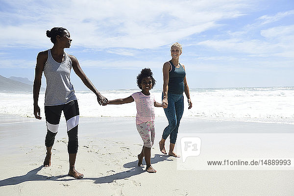 Glückliche Mutter mit Tochter und Freundin am Strand spazieren