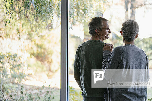 Älteres Ehepaar am Panoramafenster stehend