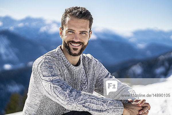 Deutschland  Bayern  Brauneck  Porträt eines lächelnden Mannes im Winter in den Bergen