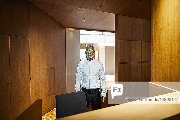 Porträt eines reifen Mannes mit Laptop am Arbeitsplatz mit Holzverkleidung