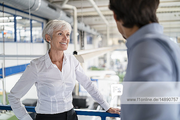 Geschäftsmann und leitende Geschäftsfrau im Gespräch in einer Fabrik