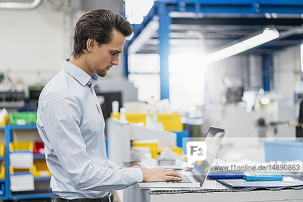 Geschäftsmann mit Laptop in einer Fabrik