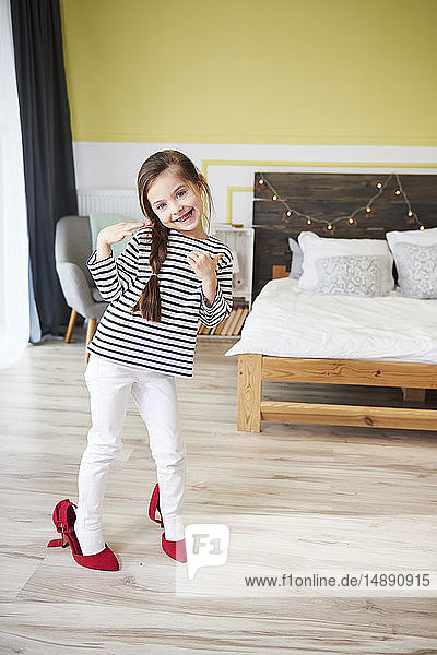 Little girl dressing up  wearing mother's red high heels