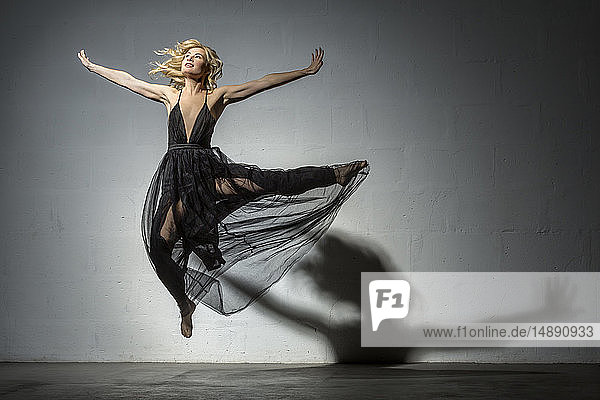 Blonde Frau tanzt in schwarzem Kleid
