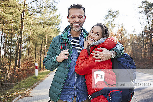 Portrait of happy couple embracing on a road in the woods during backpacking trip