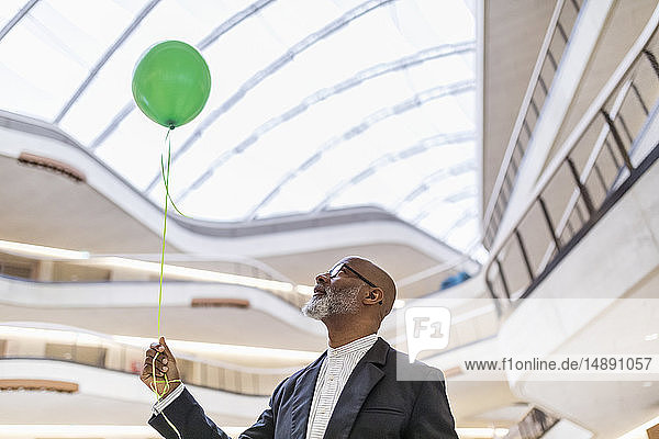 Reifer Geschäftsmann mit grünem Ballon