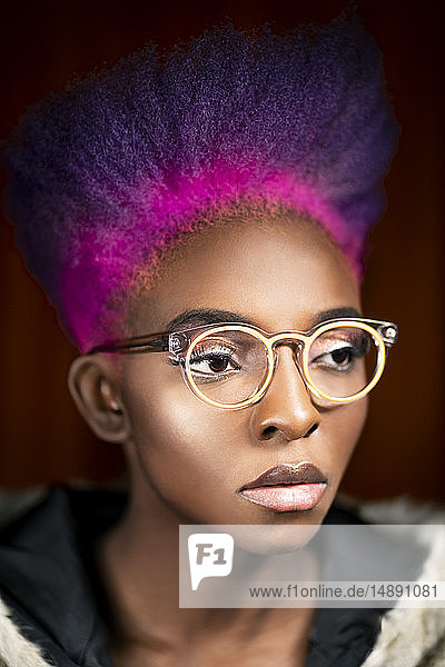 Porträt einer jungen Frau mit rosa und lila gefärbten Haaren  die eine modische Brille trägt