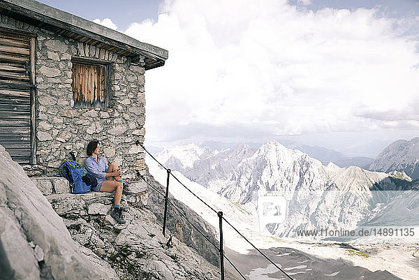 Österreich  Tirol  Frau auf Wanderung mit Rast auf Berghütte