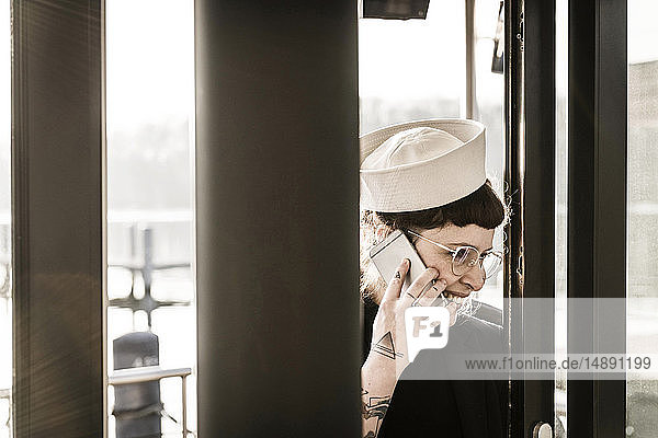 Frau mit Matrosenhut mit Smartphone auf einem Hausboot