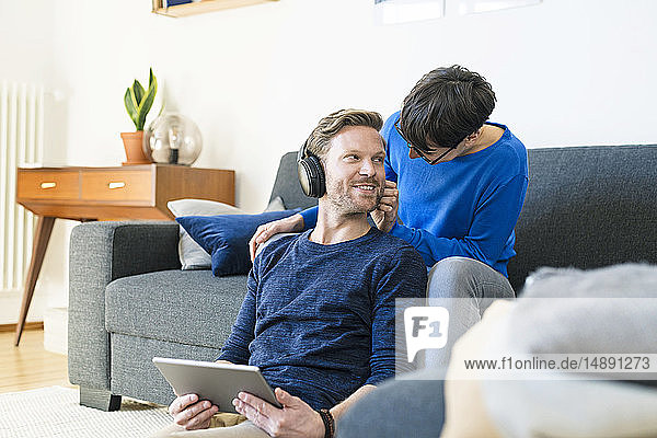 Lässiges Paar mit Kopfhörern entspannt sich auf der Couch in ihrem modernen Wohnzimmer