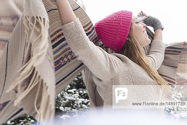 Junge Frau hält Schal im Schnee in die Höhe
