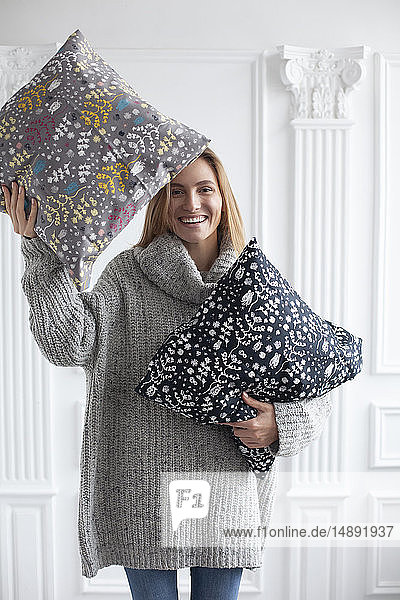 Smiling woman holding patterned cushions