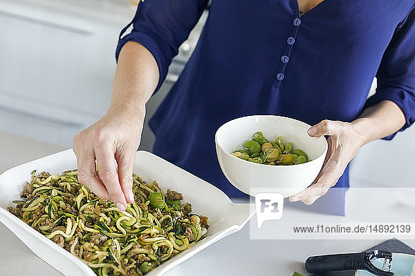 Woman preparing dinner of zucchini noodles